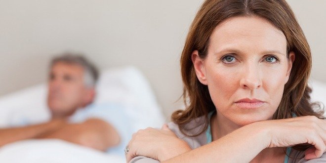 Sad woman on the bed with husband in background diabetes women sexual dysfunction
