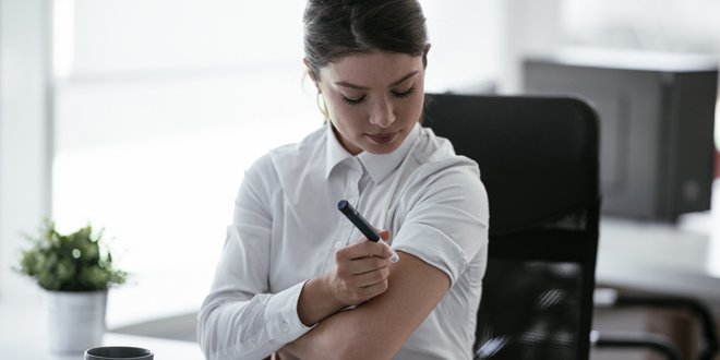 Businesswoman is giving herself an injection of insulin. woman injecting insulin