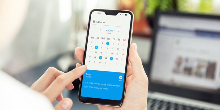 Businesswoman points smartphone screen and checks calendar on application. Application on screen created in graphic program