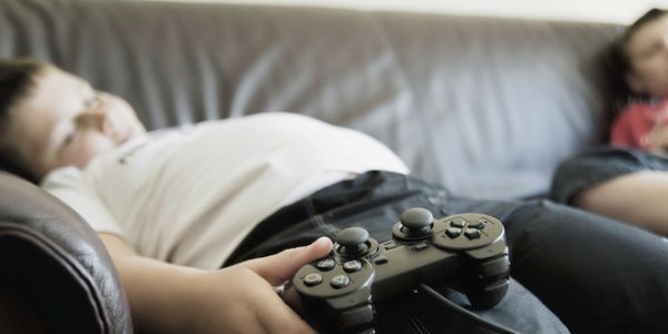 Boys Sleeping On Sofa While Holding Games Consoles Two boys sleeping on sofa while holding games consoles