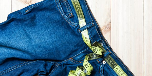 jeans and centimeter on a wooden background waist size