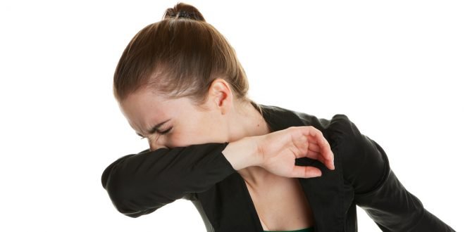 Sneezing Woman A young business woman, sneezing into her sleeve to prevent spreading germs. Shot on white background.