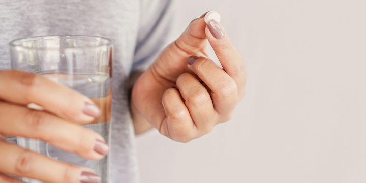 closeup woman hand taking pill 