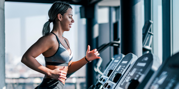 Side view of beautiful muscular woman running on treadmill. exercise and depression