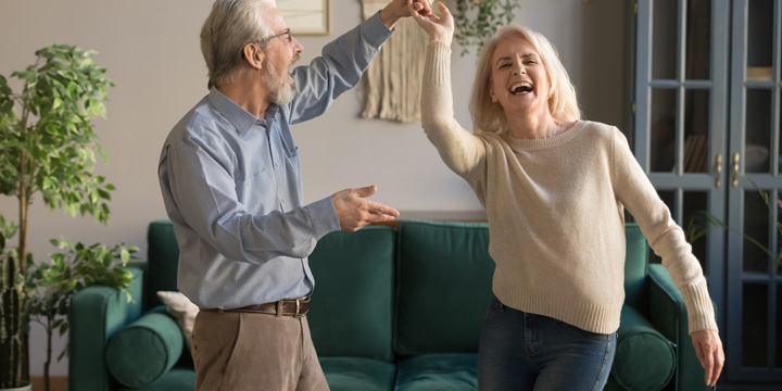 Joyful active old retired romantic couple dancing in living room