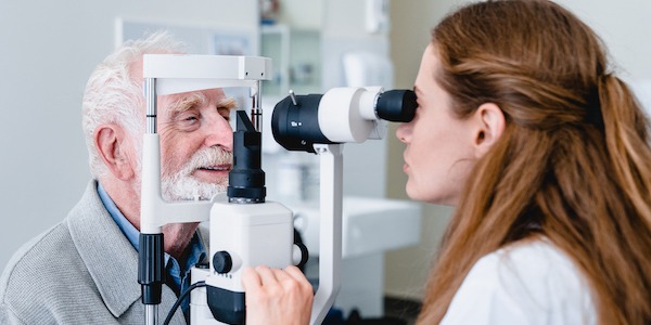 Female ophthalmic doctor diagnosing elderly patient`s sight using ophthalmic equipment